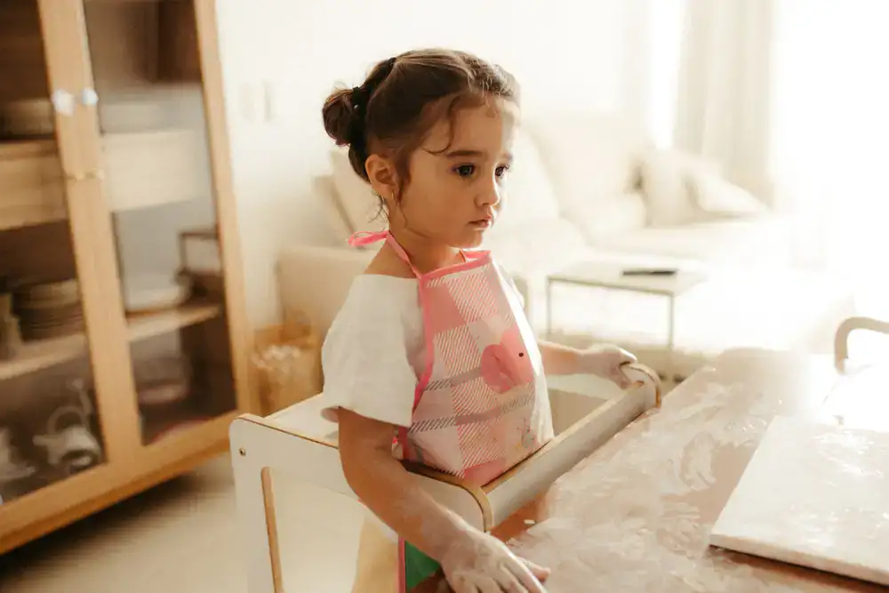 Toddler wearing a yellow waterproof apron playing at a water table