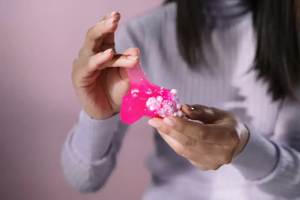 Child's hands mixing bright colorful slime in a bowl